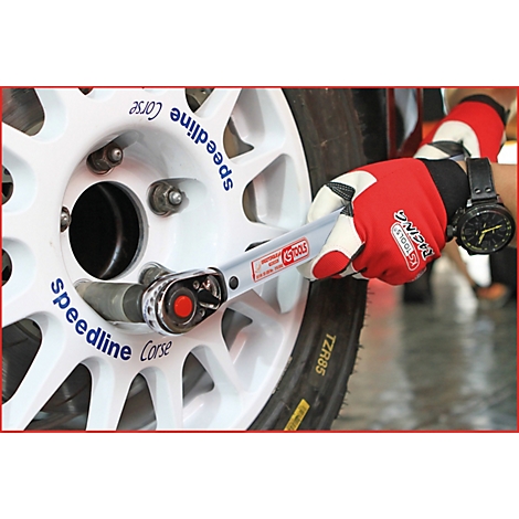 Eine Hand mit rotem Handschuh befestigt ein Rad mit einem Drehmomentschlüssel. Auf dem weißen Felgen stehen die Wörter "Speedline Corse".